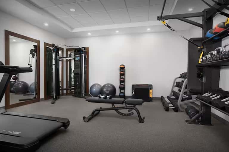 Home fitness room with treadmill, weight equipment, and resistance machines
