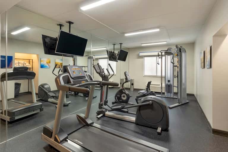 Modern hotel fitness center with cardio equipment and mirrored walls