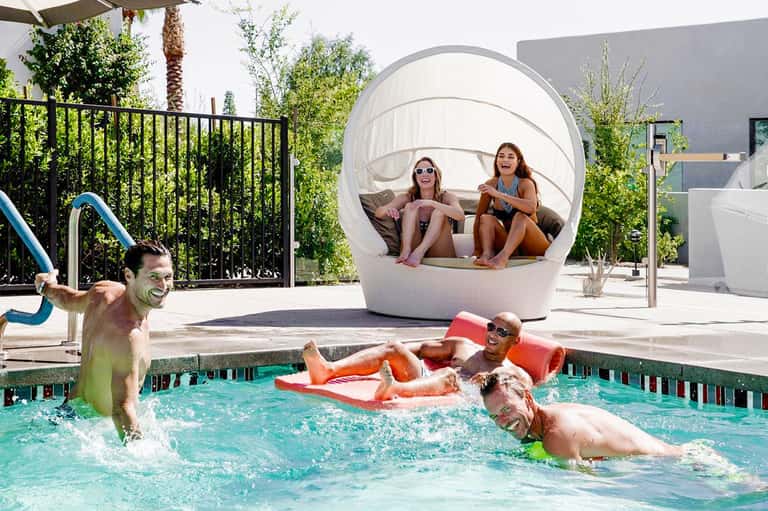 Family enjoying modern pool with spherical shade pod, lounge floats, and contemporary architecture
