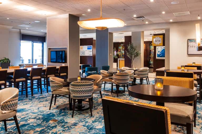 Upscale lounge with patterned armchairs, modern lighting fixtures, and contemporary decor in neutral tones