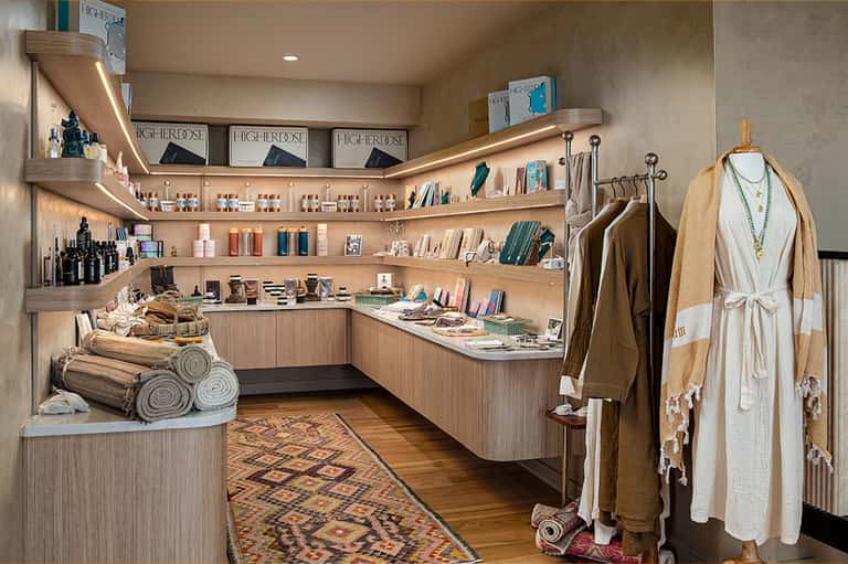 Upscale retail boutique with wooden shelving, beauty products, clothing display, and rolled towels