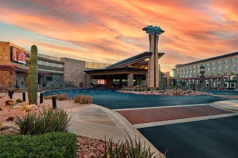 Resort entrance at sunset with turquoise water feature, modern architecture, and desert landscaping