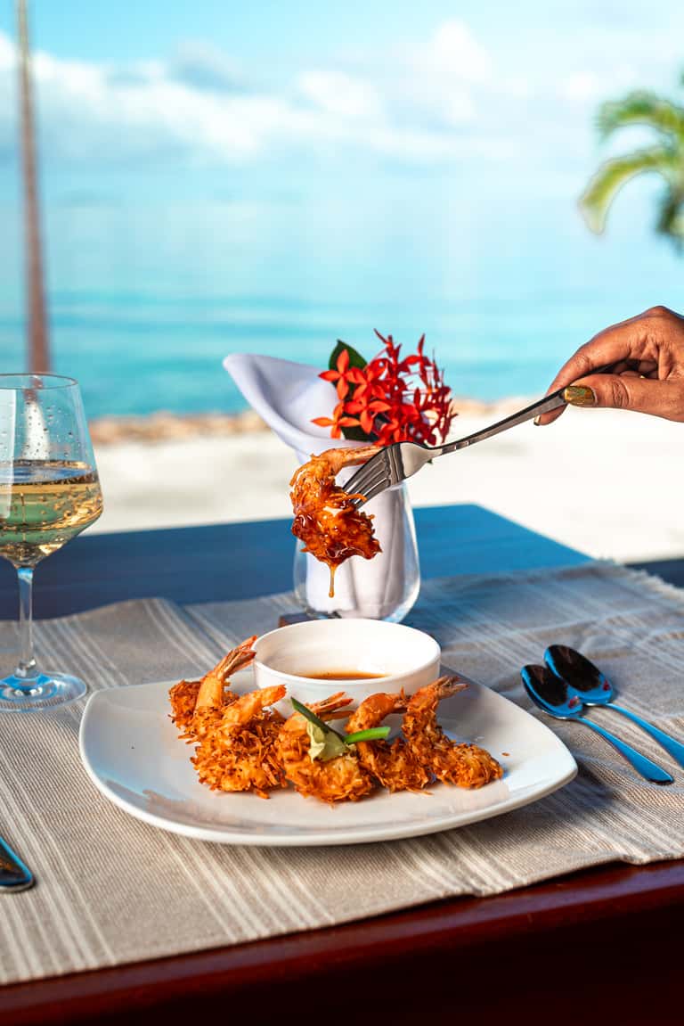 Gourmet seafood dish with ocean view backdrop, elegant beachfront dining presentation