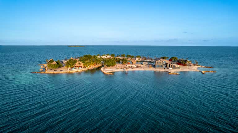 Small island resort surrounded by turquoise ocean water with palm trees and colorful buildings