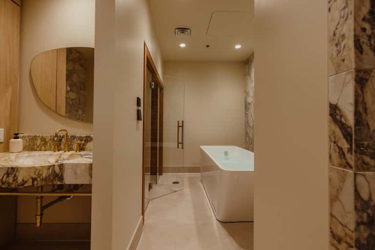Luxury bathroom with marble accents, freestanding white soaking tub, walk-in shower, and double vanity