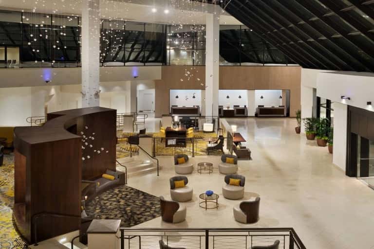 Modern hotel lobby with high ceilings, hanging light installation, and seating areas