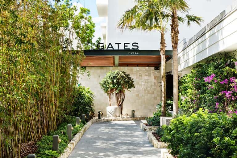 Gates Hotel entrance with modern architecture, manicured gardens, bamboo plants, and palm trees