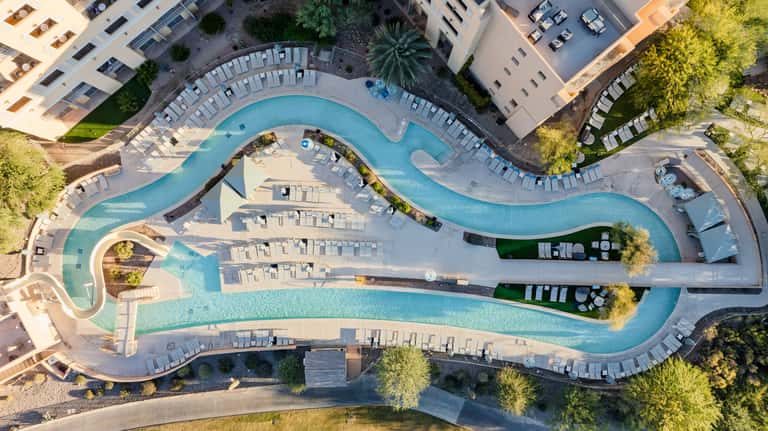 Aerial view of resort's curved pool area surrounded by loungers and palm trees