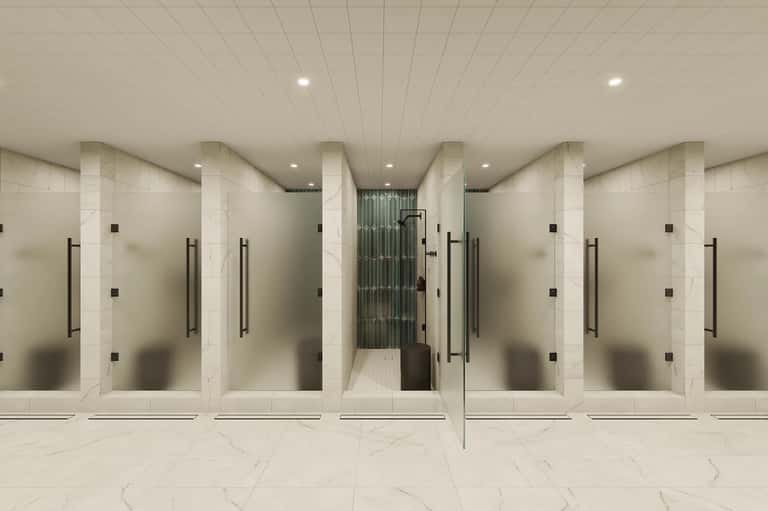 Contemporary fitness center with multiple shower stalls featuring frosted glass enclosures and marble flooring
