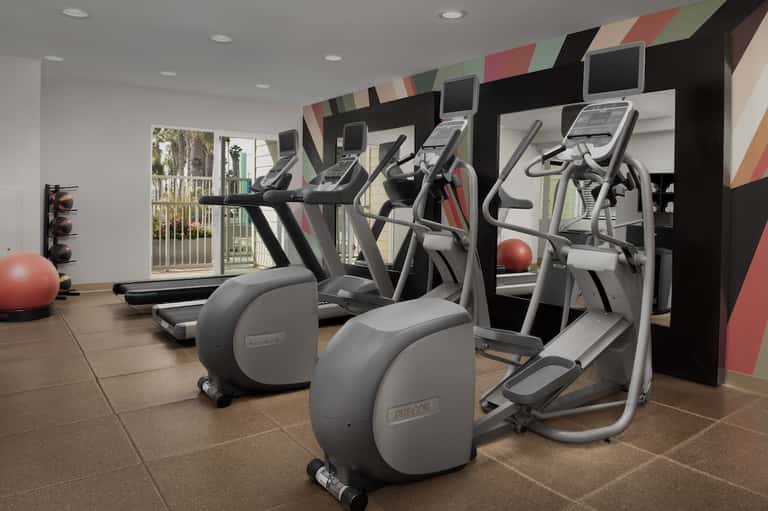 Fitness center with cardio equipment, exercise bikes, and red accent wall design elements