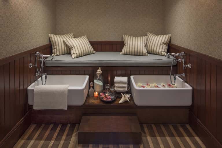 Spa relaxation room with dual soaking tubs, striped pillows, candles, and wood accents