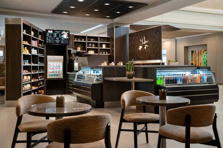 Modern café interior with dark wood cabinetry, display cases, seating area, and contemporary furnishings