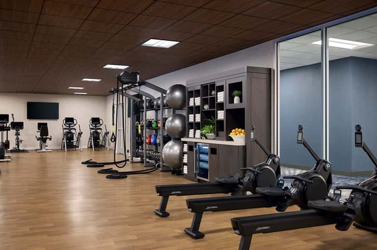 Modern hotel fitness center with exercise bikes, equipment, and storage shelving