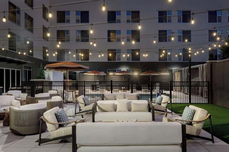 Evening courtyard lounge with firepit, seating, umbrellas, and string lights