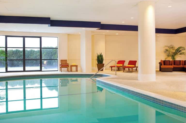 Indoor swimming pool with large windows, lounge seating area, and modern architecture