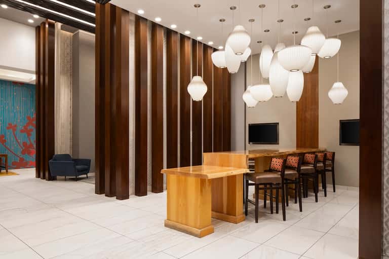 Modern hotel lobby with wood accent walls, elegant pendant lights, seating area, and contemporary design