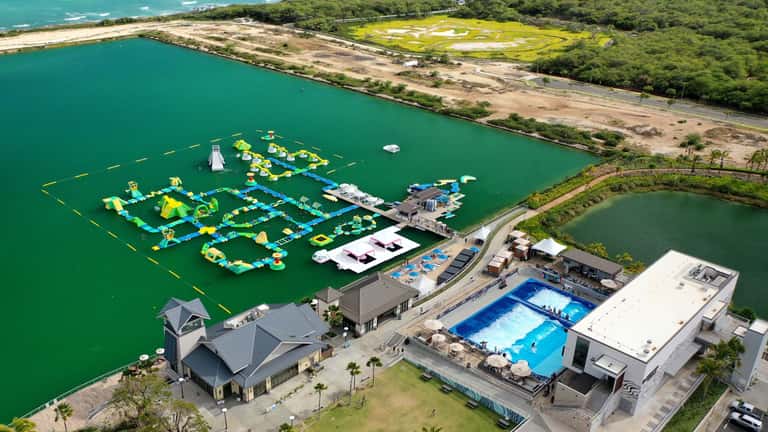 Aerial view of waterpark and resort complex with inflatable attraction, pools, lagoon, beach, and golf course