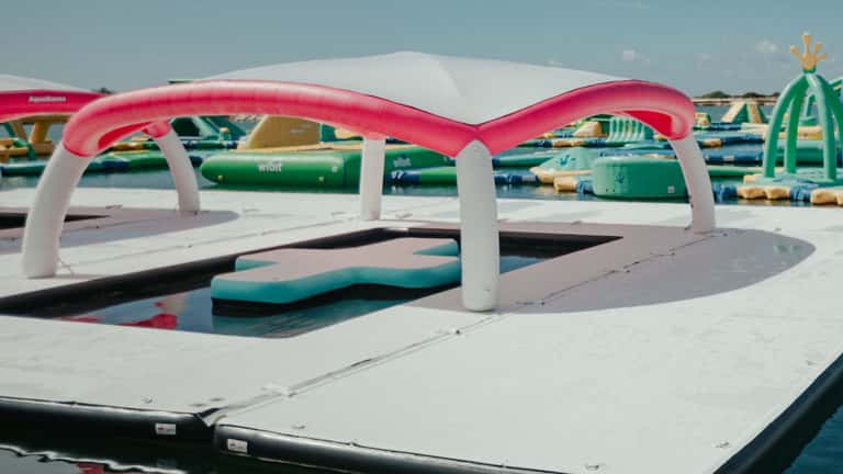 Colorful inflatable water park structure with pink arch over shallow pool area