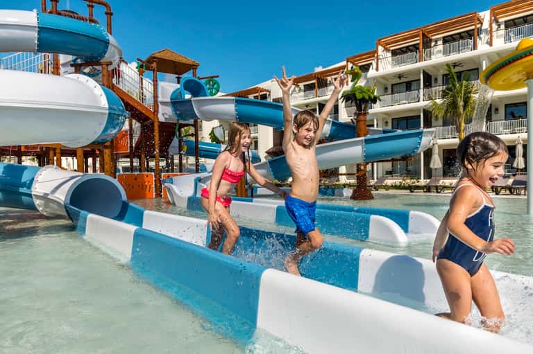 Family fun pool area with colorful water slides, shallow children's pools, and multi-story resort buildings