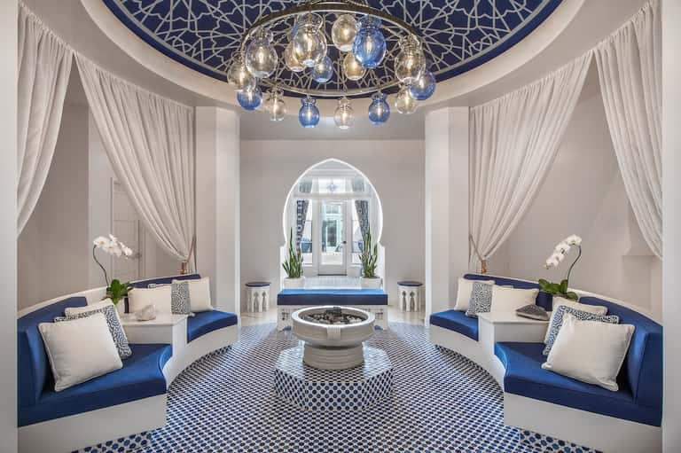 Luxurious spa sanctuary with blue and white decor, ornate chandelier, marble fountain, and archway