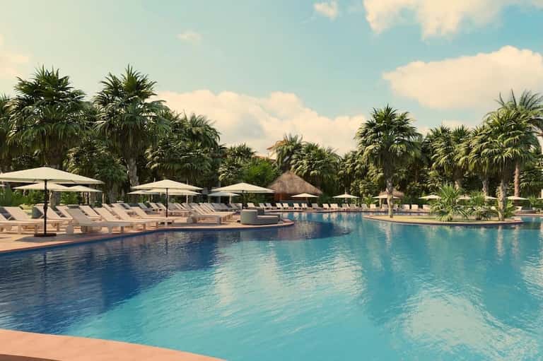 Resort pool surrounded by palm trees, white umbrellas, lounge chairs, and clear blue water