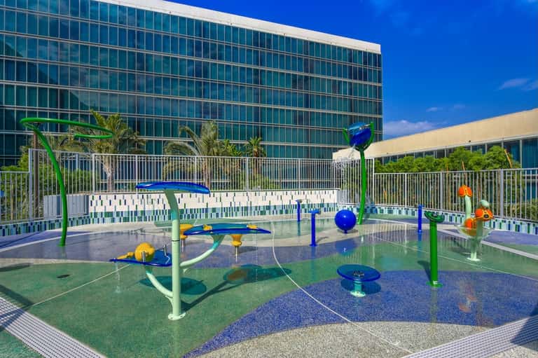 Colorful splash pad play area for children on hotel rooftop with city views