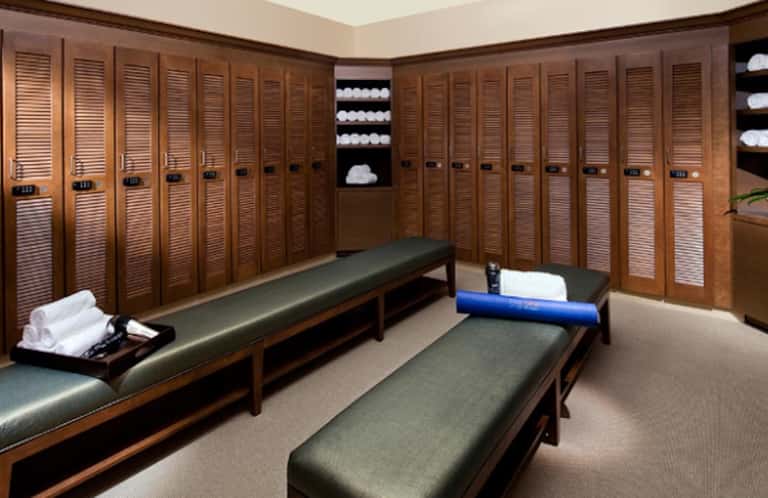 Elegant locker room with wooden cabinetry, towel storage shelves, and cushioned bench seating