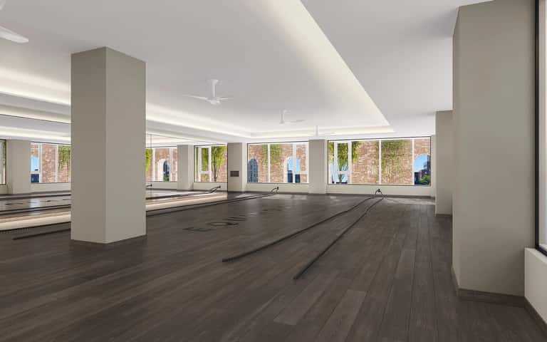 Spacious fitness center with mirrored walls, wooden flooring, and bright windows
