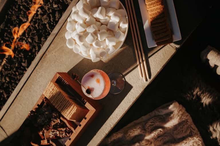 Overhead view of spa amenities including marshmallows, cocktail, and relaxation items on textured surface