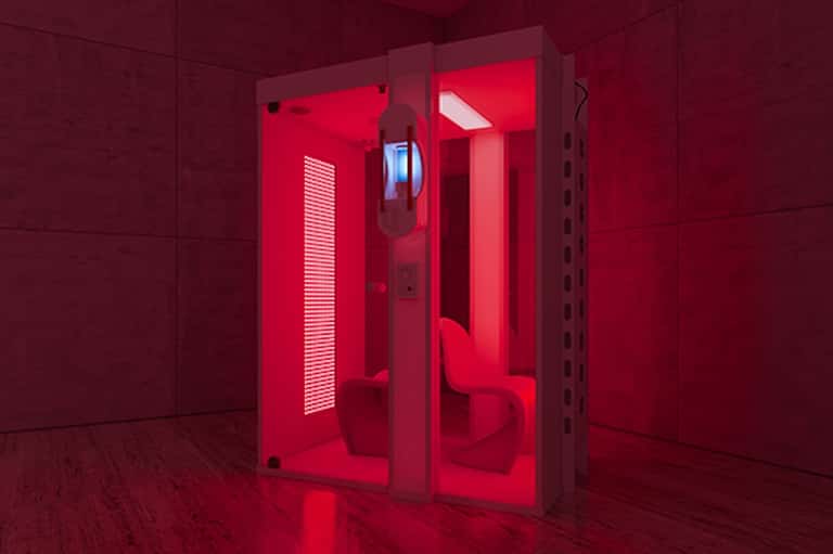 Red-lit infrared sauna pods in spa facility with glass doors