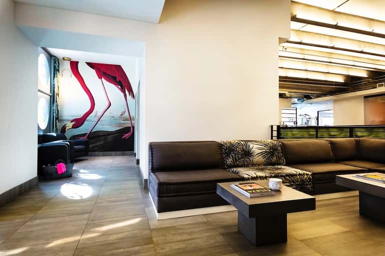 Modern lounge with black sectional sofa, abstract wall art, and wooden ceiling details