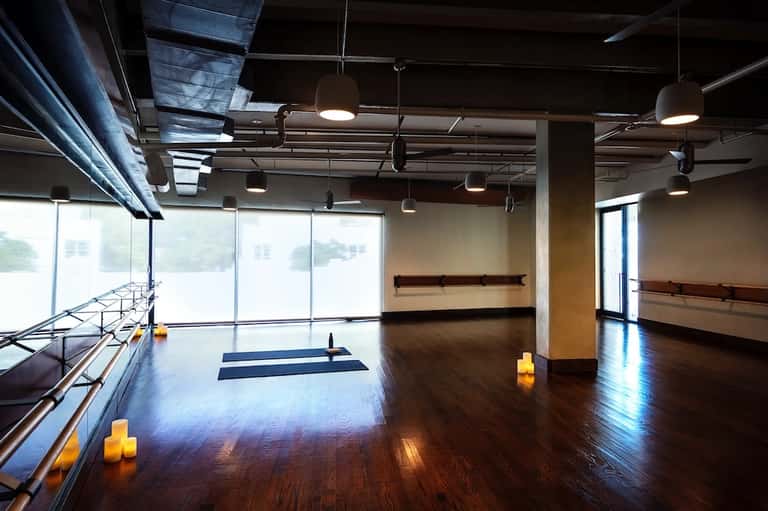 Fitness studio with wooden flooring, mirrors, windows, and candles for yoga class
