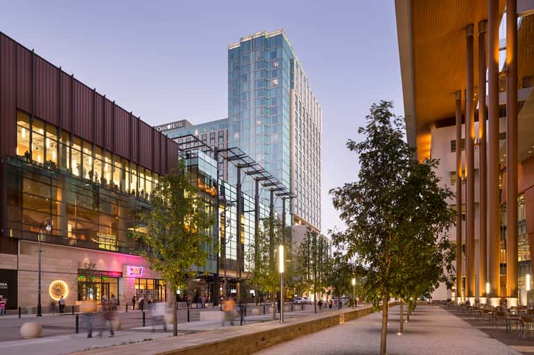 Urban downtown plaza at dusk with modern buildings, shops, and pedestrian walkway