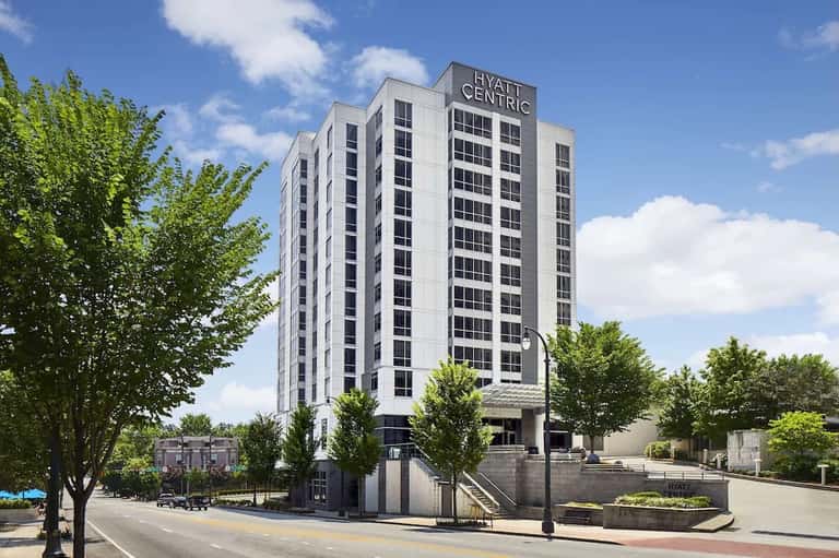 Hyatt Centric hotel high-rise building with white facade, dark windows, and surrounding trees