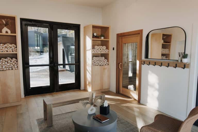 Modern spa lounge with shelving, wooden doors, and black framed mirror