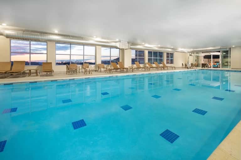 Indoor swimming pool with lane markings and large windows overlooking cityscape