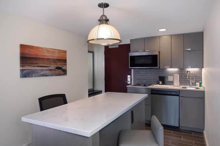 Modern kitchenette with marble countertop, gray cabinetry, and pendant light