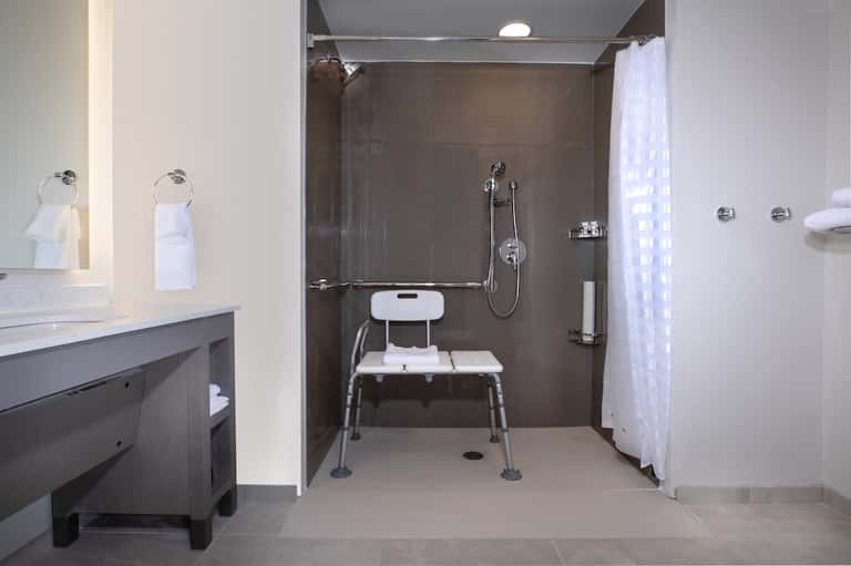 Accessible bathroom with roll-in shower, grab bars, and bench seating for guests with mobility needs.
