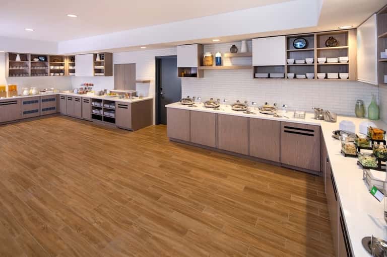 Large hotel kitchen and breakfast area with display counters and wood flooring