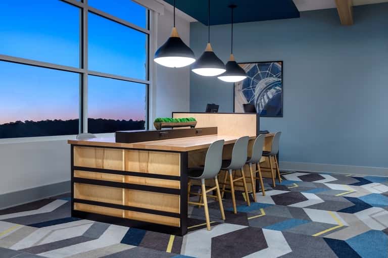 Modern hotel reception desk with wood paneling, pendant lights, and panoramic window view