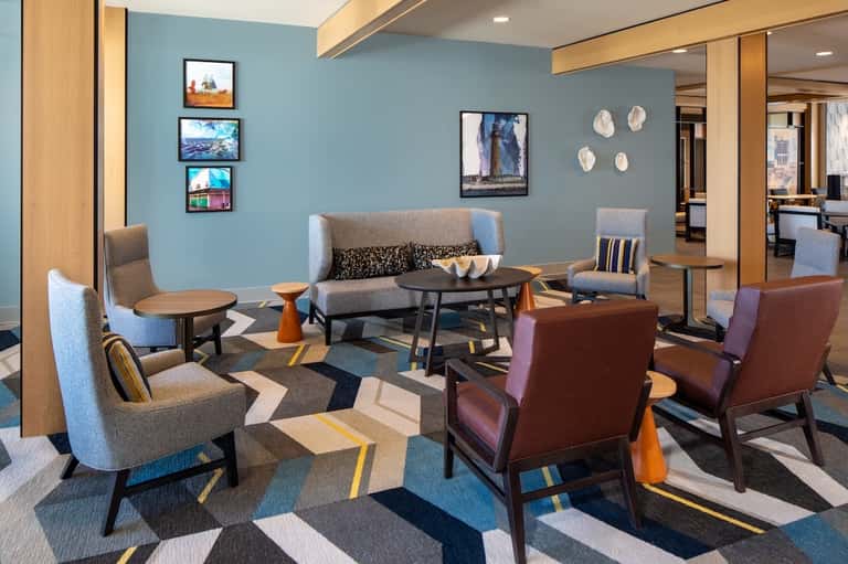 Colorful modern lounge with blue walls, geometric carpet, and contemporary furniture