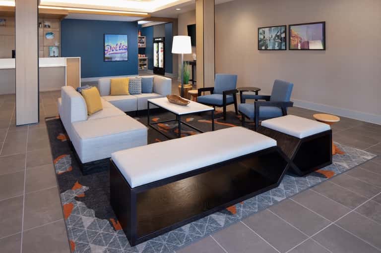 Contemporary hotel lobby with blue accent wall, modular seating, reception desk, and casual lounge area
