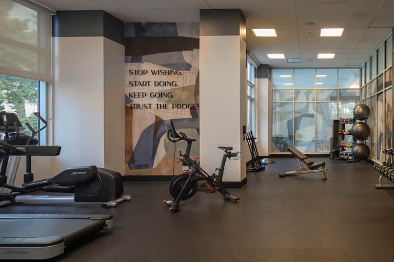 Hotel fitness center with cardio equipment, motivational wall graphics, and floor-to-ceiling windows
