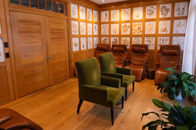 Warm wooden media room with leather seating, wall of framed botanical prints, and modern entertainment setup