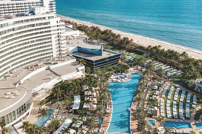 Beachfront resort with curved pool, modern architecture, and high-rise hotel building