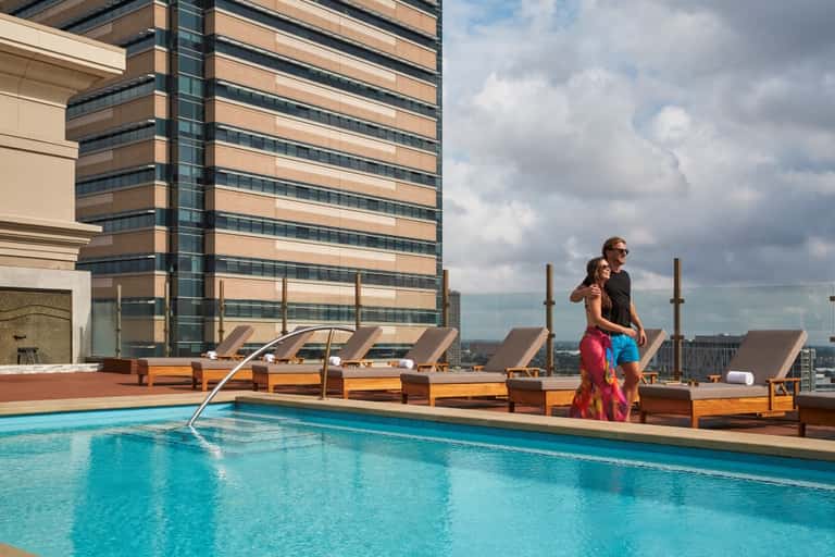 Rooftop pool at high-rise hotel with wood lounge chairs and city skyline views