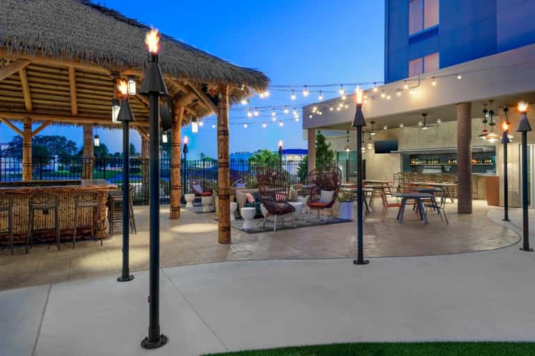 Waterfront rooftop terrace at dusk with lounge seating, pergola, and string lights