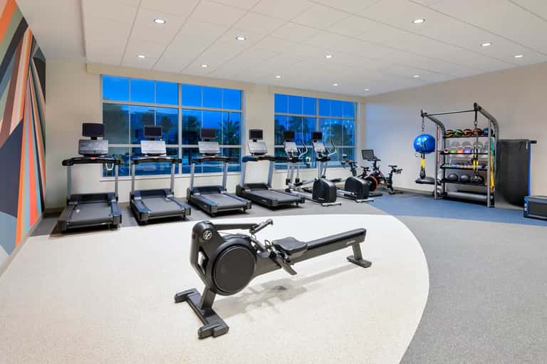 Fitness center with treadmills, exercise bikes, rowing machine, weights, and large windows overlooking grounds