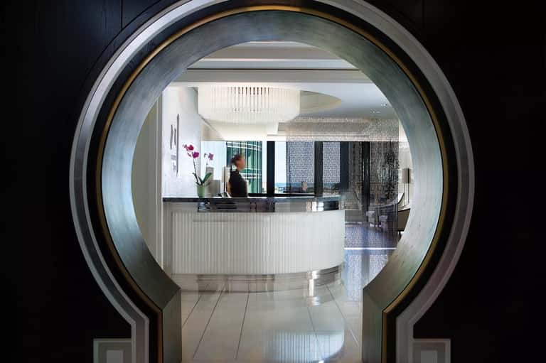 Hotel reception desk viewed through modern circular archway with staff member at counter