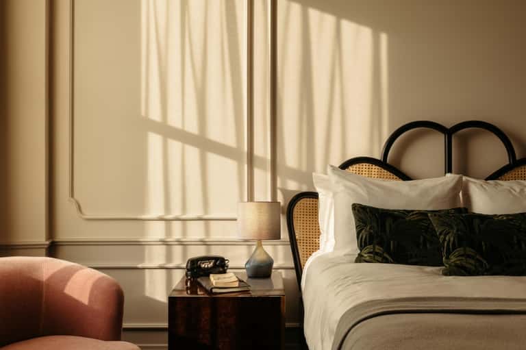 Luxury bedroom with sunlit windows, cream curtains, black headboard bed, and minimalist decor